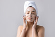 © Mountains Hunter - Beauty portrait of woman in white towel on head applies cream to the face. Skincare cleansing eco organic cosmetic spa relax concept.