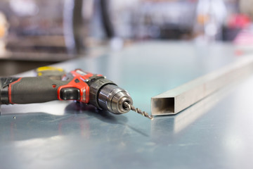 Electrical screwdriver and profile pipe on the factory table