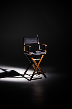 Directors Chair Stands In The Beam Of Light. Space For Text. Vacant Chair. The Concept Of Selection And Casting. Shadow And Light.