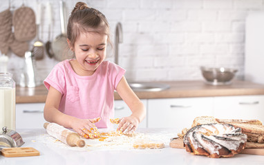 A cute little girl is cooking homemade cakes in the kitchen.