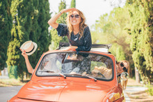 Three girls best friends enjoying summer trip in Tuscany with red vintage car
