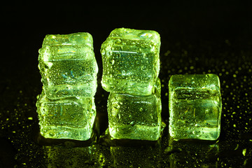 Wall Mural - Green ice cubes on black table background.