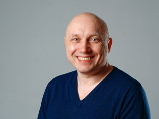 Portrait of a bald cheerful man on a gray background