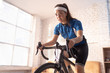 © torwaiphoto - Asian woman cyclist. She is exercising in the house.By cycling on the trainer and play online bike games