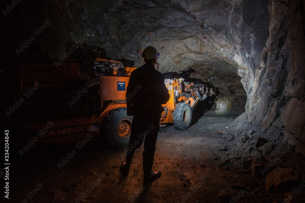 Man miner in underground quartz mine tunnel with scoop machine - obrazy, fototapety, plakaty 