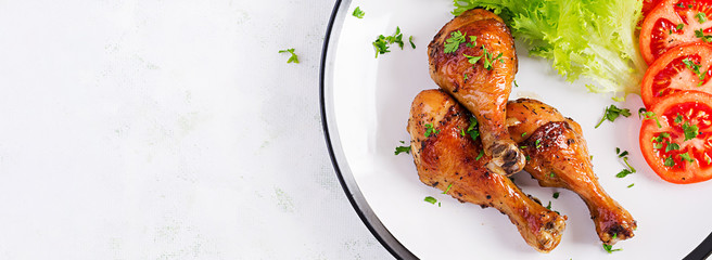 Wall Mural - Grilled chicken legs with spices and fresh vegetables. Baked drumsticks. Top view, banner