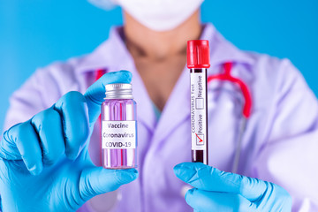 Doctor holds COVID 19  vaccine and blood test tube in her hand, Vaccine it use for prevention, immunization and treatment from COVID-19.