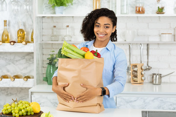 Wall Mural - Satisfied afro girl holding paper bag with food