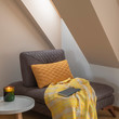 Cozy nook by the window with yellow blanket and pillow on a coach