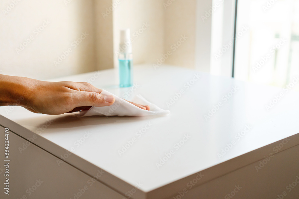 Woman hand cleaning headboard with disinfectant wet wipe and alcohol spray in bedroom at home. Concept of disinfecting surfaces from bacteria or viruses. Close up - obrazy, fototapety, plakaty 