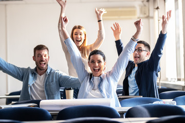 Wall Mural - Group of happy students with hands raised  up,smiling and looking at camera.