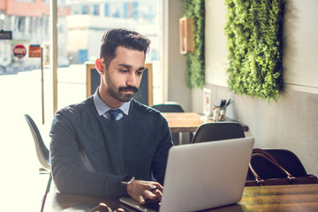 Wall Mural - Young handsome Businessman working on laptop in cafe.