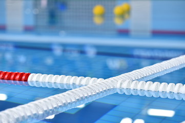 Swimming pool lane lines and floating on a still water with polo balls in background before a match