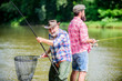 Feel the Gear. father and son fishing. hobby and sport activity. Trout bait. summer weekend. mature men fisher. two happy fisherman with fishing rod and net. male friendship. family bonding