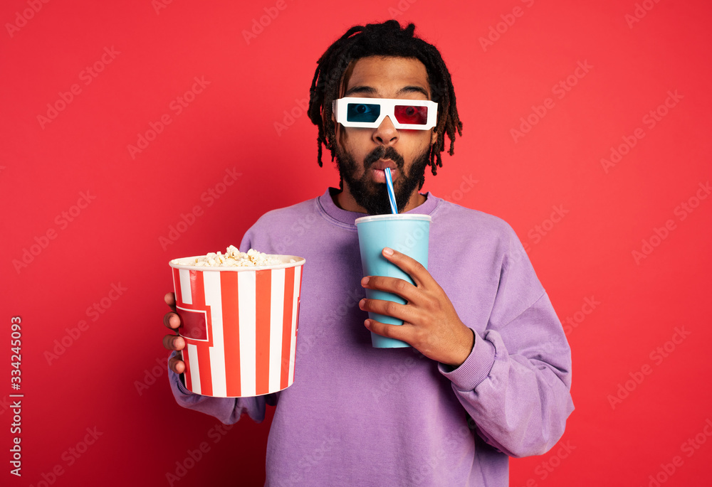 Boy has fun watching a film. Concept of entertainment and streaming tv. red background - obrazy, fototapety, plakaty 