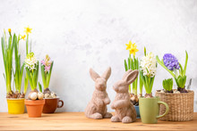 Easter Home Decor Concept With Potted Blooming Flowers And Decorative Rabbit Figurines