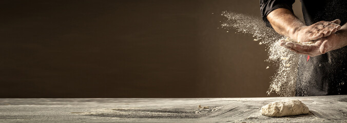 Photo of flour and men hands with flour splash. Cooking bread. Kneading the Dough. Isolated on dark background. Empty space for text