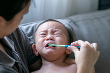 Asian Mother Is Helping To Brush Teeth For Her Baby Crying Unhappy When Brushing Teeth,Concept Take Care Dental Health.