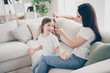 © deagreez - Profile photo of pretty little girl young mommy sitting cozy sofa weekend morning brushing long brown hair talking about school friends casual clothing home indoors