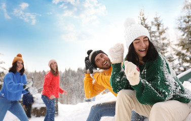 Wall Mural - Group of friends playing snowballs outdoors. Winter vacation