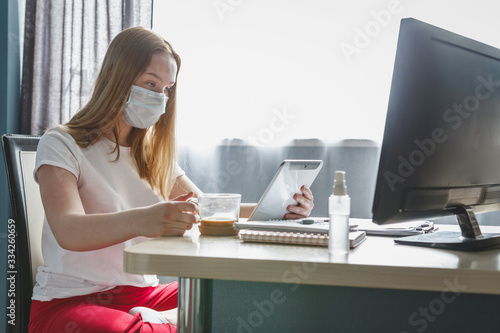 Coronavirus. Quarantine. Remote work home.  girl  table in a mask and gloves works. Home office, social distance. Online training, education and freelance work. Coronavirus pandemic world stay home
