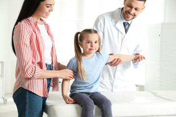 Poster - Professional orthopedist examining little patient's arm in clinic