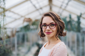 Woman researcher standing in greenhouse, looking at camera.