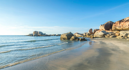 Wall Mural - Beach rock with water wave blue skies background