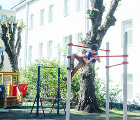 little cute blond boy hanging on playground outside, alone training with fun, lifestyle children concept