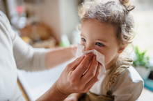 Unrecognizable Father Blowing Nose Of Small Sick Daughter Indoors At Home.