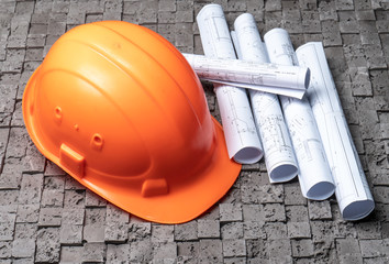 Orange worker helmet on grey wall background