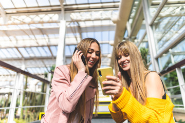 Wall Mural - Two Female Friends Using Cellphone Together.