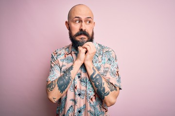 Sticker - Handsome bald man with beard and tattoo wearing casual floral shirt over pink background laughing nervous and excited with hands on chin looking to the side