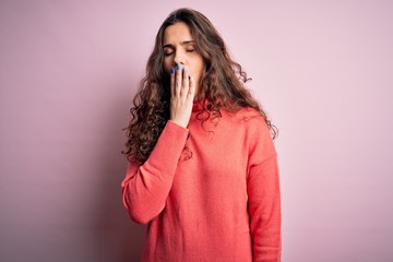 Sticker - Young beautiful woman with curly hair wearing turtleneck sweater over pink background bored yawning tired covering mouth with hand. Restless and sleepiness.