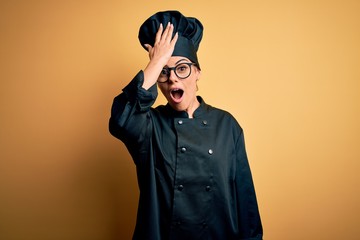 Poster - Young beautiful brunette chef woman wearing cooker uniform and hat over yellow background surprised with hand on head for mistake, remember error. Forgot, bad memory concept.