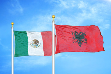 mexico and albania two flags on flagpoles and blue cloudy sky