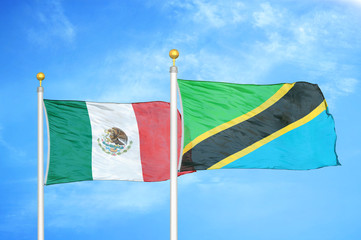 Mexico and Tanzania two flags on flagpoles and blue cloudy sky