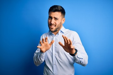 Sticker - Young handsome man wearing elegant shirt standing over isolated blue background disgusted expression, displeased and fearful doing disgust face because aversion reaction. With hands raised