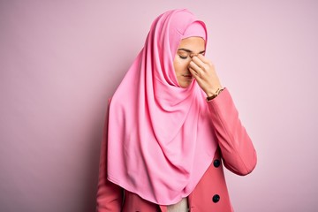 Poster - Young beautiful girl wearing muslim hijab standing over isolated pink background tired rubbing nose and eyes feeling fatigue and headache. Stress and frustration concept.