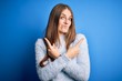 © Krakenimages.com - Young beautiful redhead woman wearing casual sweater over isolated blue background Pointing to both sides with fingers, different direction disagree