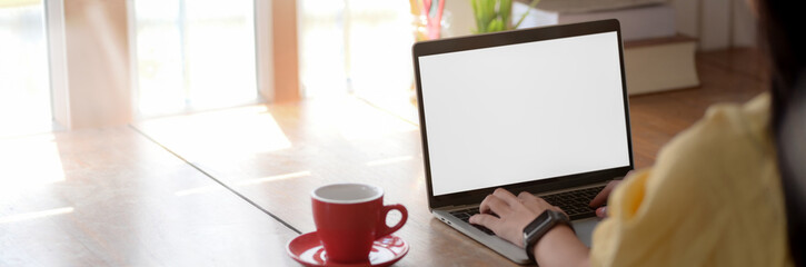 Cropped shot of young female college student typing on blank screen laptop