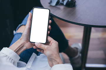 Mockup image blank white screen cell phone.woman hand holding texting using mobile on desk at coffee shop.background empty space for advertise text.people contact marketing business,technology