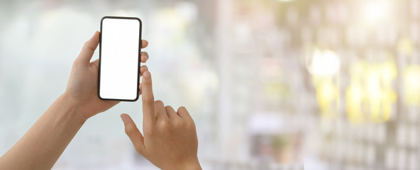 Wall Mural - Cropped shot of a man touching on blank screen smartphone in blurred glass wall office