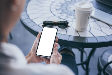 Mockup image blank white screen cell phone.woman hand holding texting using mobile on desk at coffee shop.background empty space for advertise text.people contact marketing business,technology