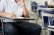 © panitan - high school,university student study.hands holding pencil writing paper answer sheet.sitting lecture chair taking final exam attending in examination classroom.concept scholarship for education abroad