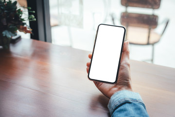 Mockup image blank white screen cell phone.woman hand holding texting using mobile on desk at coffee shop.background empty space for advertise text.people contact marketing business,technology