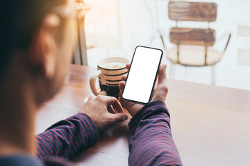 cell phone Mockup image blank white screen.man hand holding texting using mobile on desk at coffee shop.background empty space for advertise text.people contact marketing business,technology