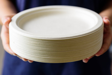 Stack of Biodegradable plate, Compostable plate or Eco friendly disposable plate holding by hand