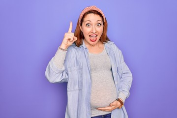 Poster - Young beautiful redhead pregnant woman expecting baby over isolated purple background pointing finger up with successful idea. Exited and happy. Number one.