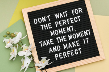 Wall Mural - Don't wait for the perfect moment, take the moment and make it perfect. Motivational quote on letter board frame and flower orchid on green background. Concept inspirational quote